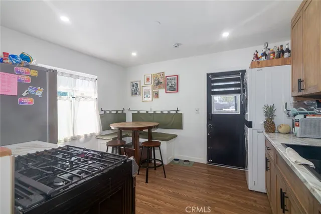 a kitchen with stainless steel appliances granite countertop a stove top oven a refrigerator and dining table with wooden floor