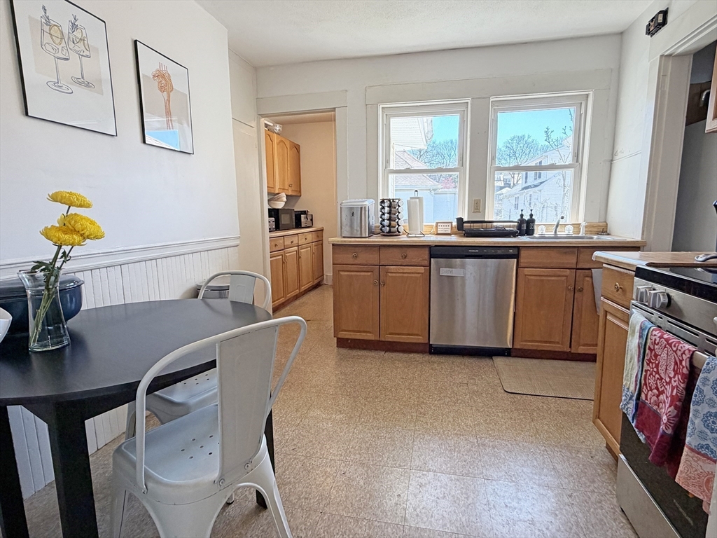 12-14 Nottingham Street Newton, MA 02459 - Photo 10 of 29 a kitchen with stainless steel appliances granite countertop a stove a sink a microwave dining table and chairs