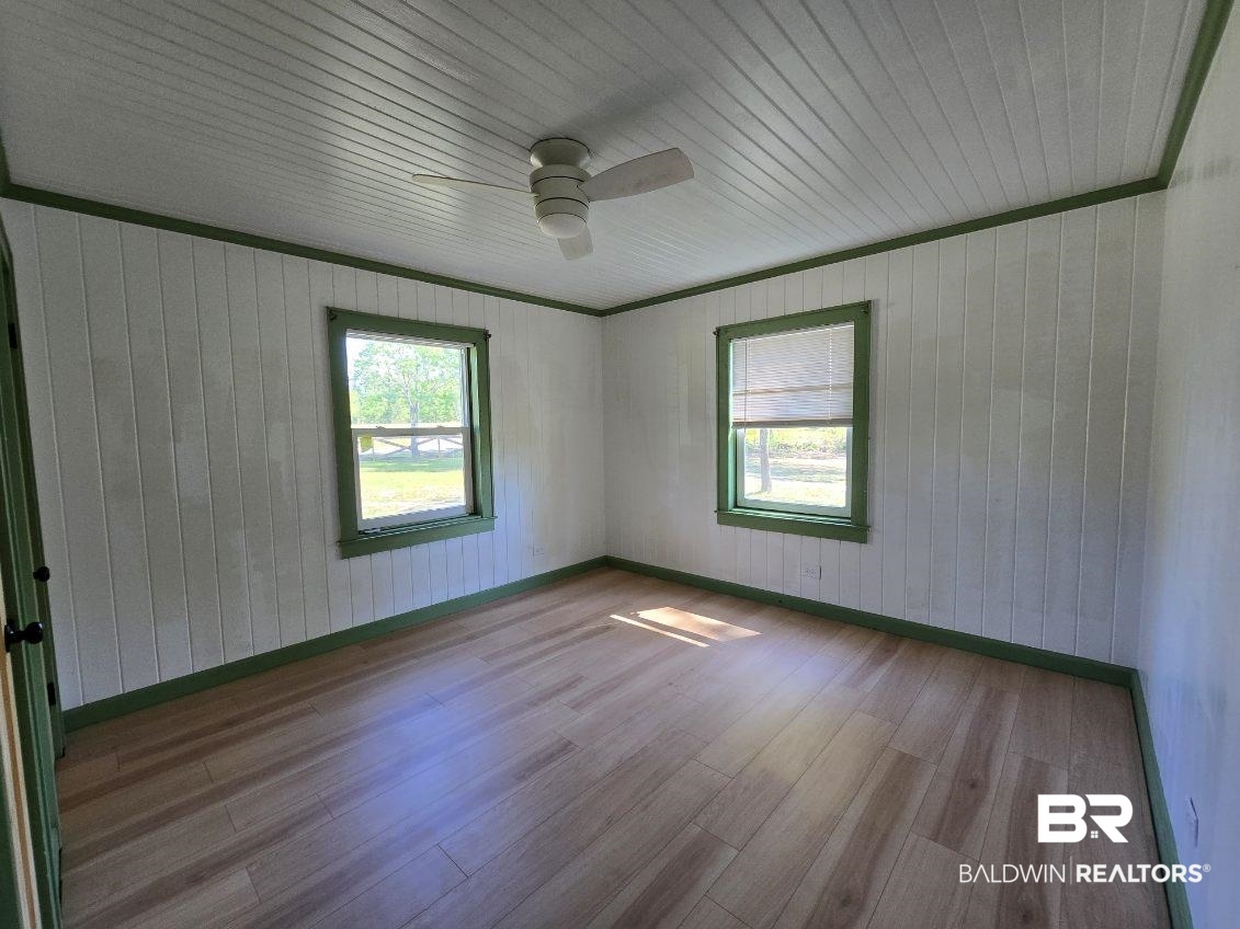 6464 Ridge Road Brewton, AL 36426 - Photo 11 of 14 Spare room with plenty of natural light, wooden walls, wood finished floors, ceiling fan, and baseboard heating