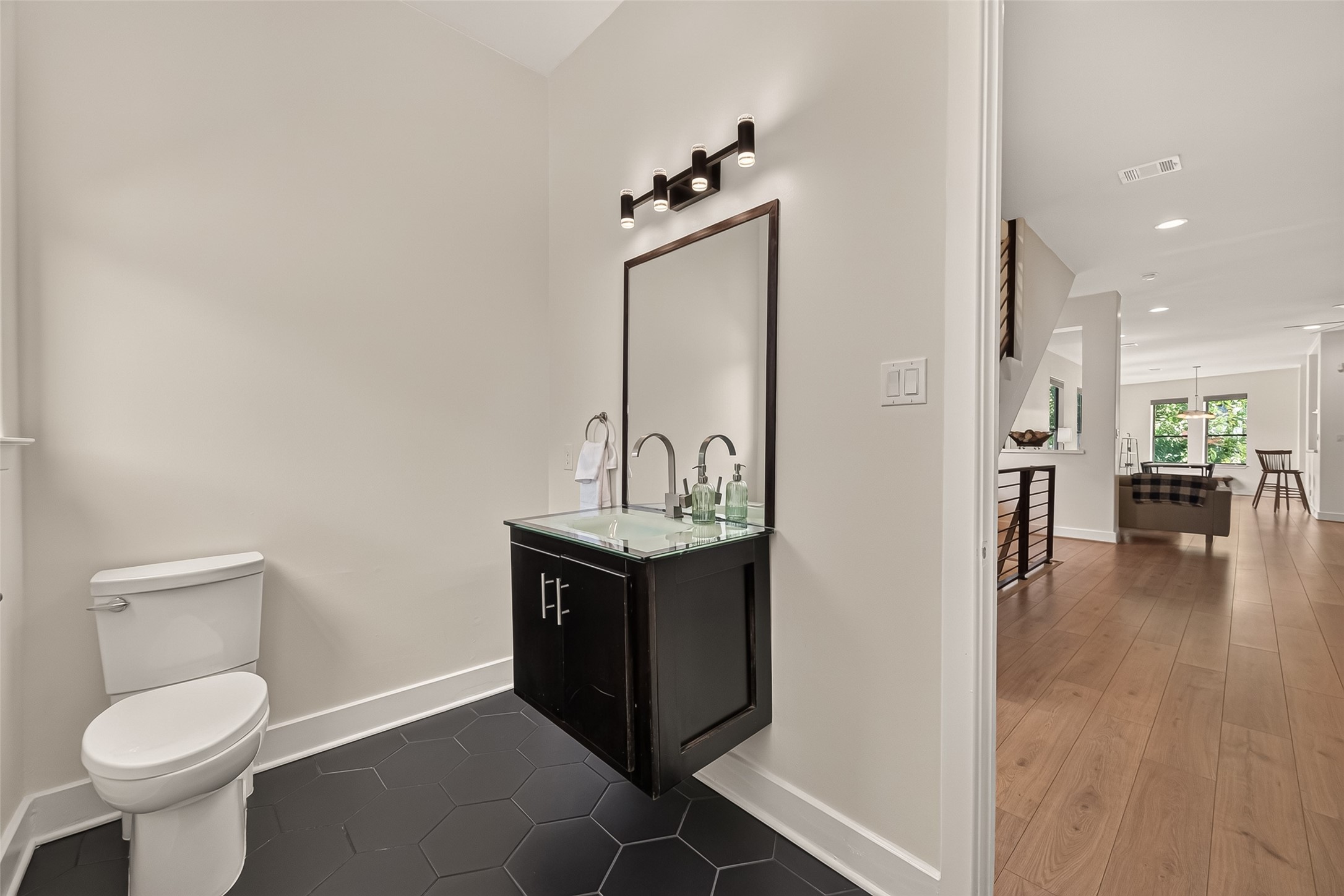 1767 Michigan Street Houston, TX 77006 - Photo 16 of 33 The powder bathroom with a sleek, floating vanity and a large mirror, complemented by a hexagonal tile floor.