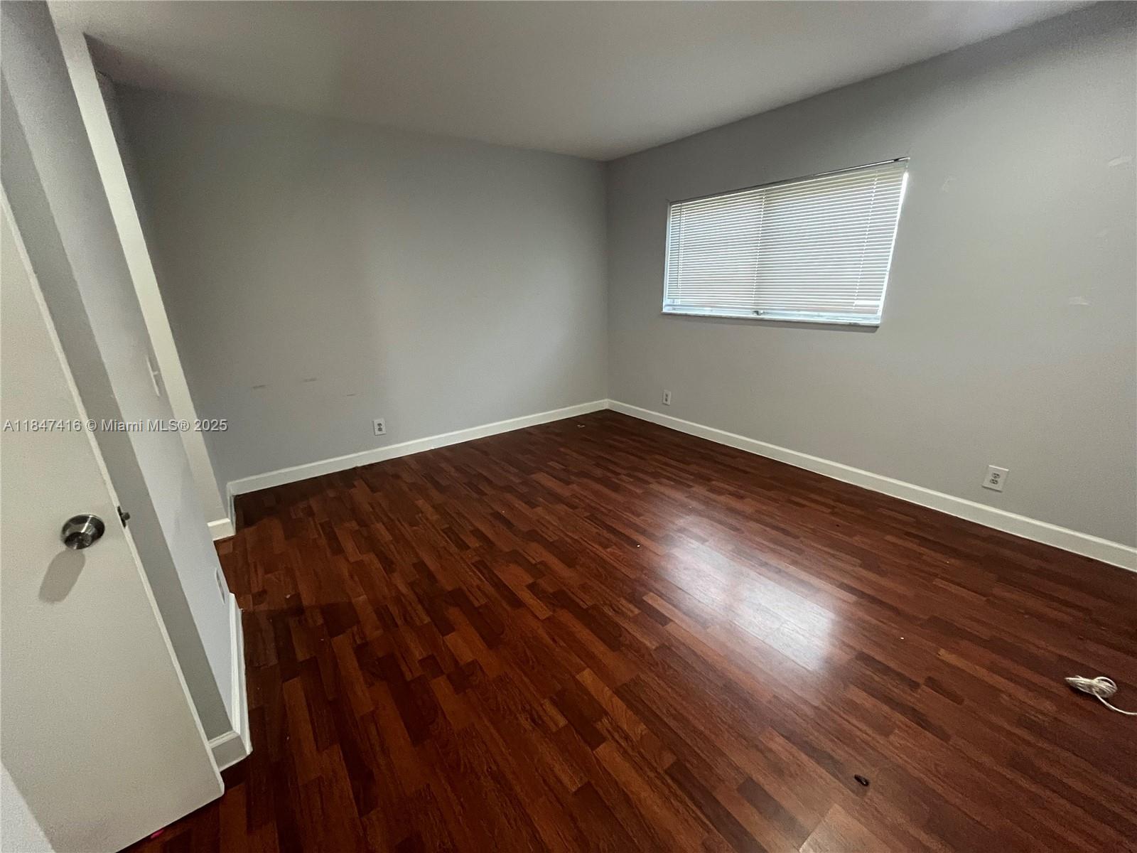 8404 West Sample Road, Unit 131 Coral Springs, FL 33065 - Photo 26 of 36 an empty room with wooden floor and windows