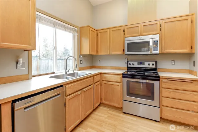 a kitchen with stainless steel appliances granite countertop a sink a stove a microwave and wooden cabinets