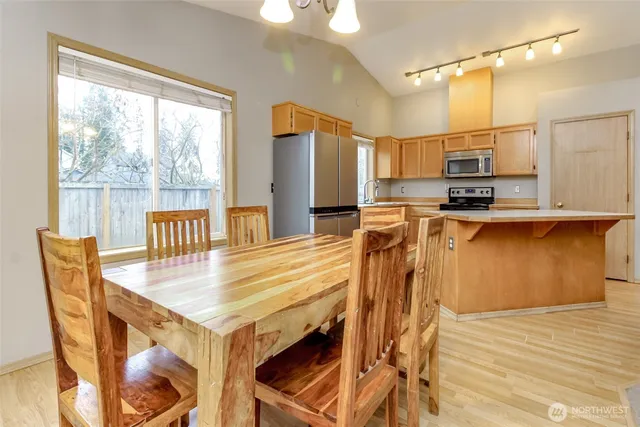 a kitchen with stainless steel appliances granite countertop a stove top oven a sink a dining table and chairs with wooden floor