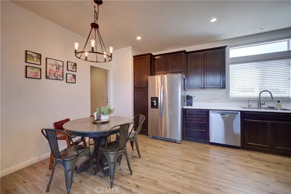 a kitchen with stainless steel appliances a dining table chairs and wooden floor