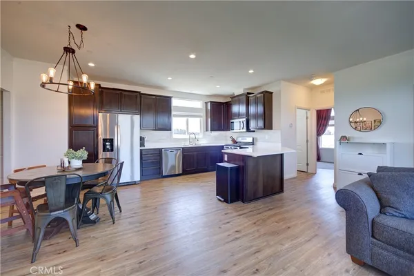 a living room with stainless steel appliances kitchen island granite countertop furniture wooden floor and kitchen view