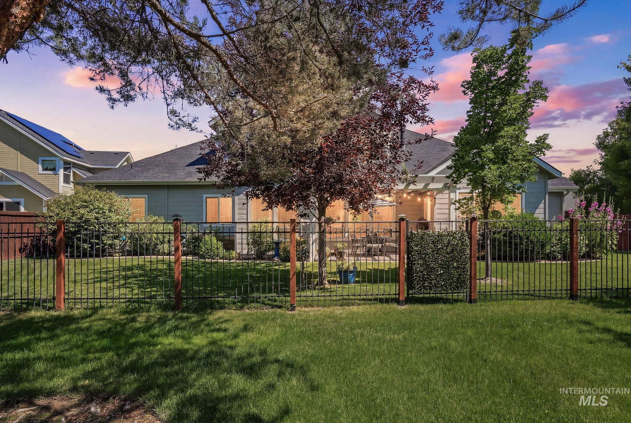 3969 North Hollymount Way Meridian, ID 83646 - Photo 47 of 47 Rear exterior featuring a black metal fence with wood posts, a manicured lawn, and mature trees