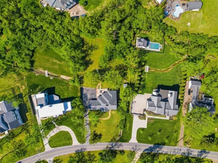 an aerial view of residential houses with outdoor space and trees all around