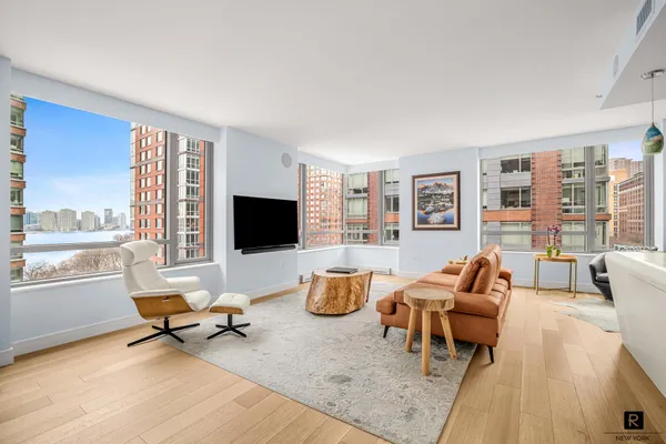 a living room with furniture floor to ceiling window hardwood floor and a flat screen tv