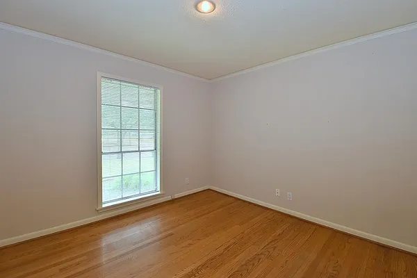 an empty room with wooden floor closet and windows