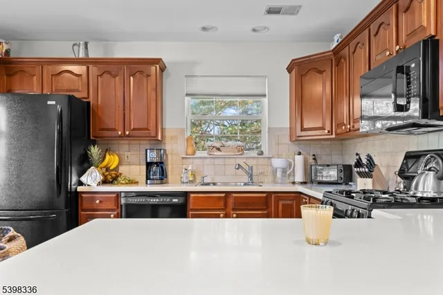 a kitchen with stainless steel appliances a sink a stove a refrigerator a sink a counter space and cabinets