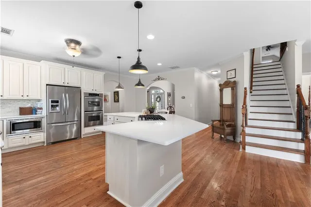 a large kitchen with stainless steel appliances a large counter top a sink a stove and a refrigerator