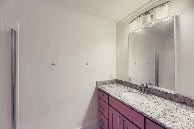 a bathroom with a granite countertop sink and a mirror
