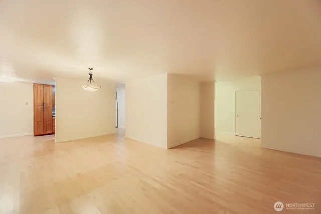 a view of an empty room with kitchen and a window