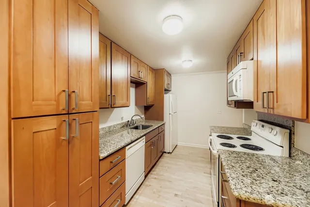 a kitchen with stainless steel appliances granite countertop a refrigerator a stove and a wooden cabinets