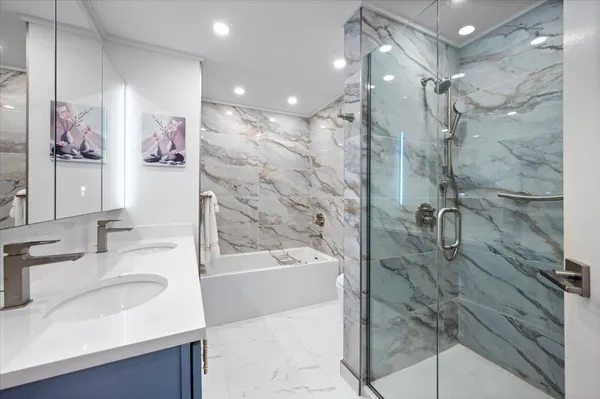 a bathroom with a sink vanity granite tub shower and a mirror