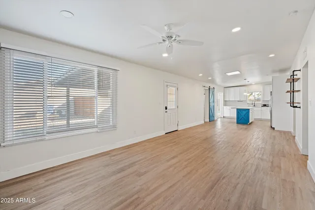 a view of an empty room with a window and wooden floor