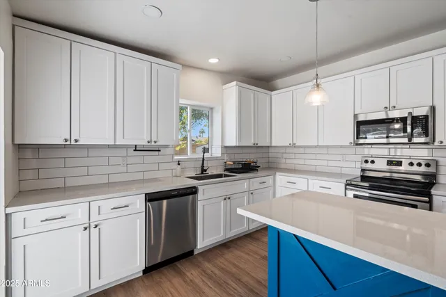 a kitchen with stainless steel appliances white cabinets sink and wooden floor