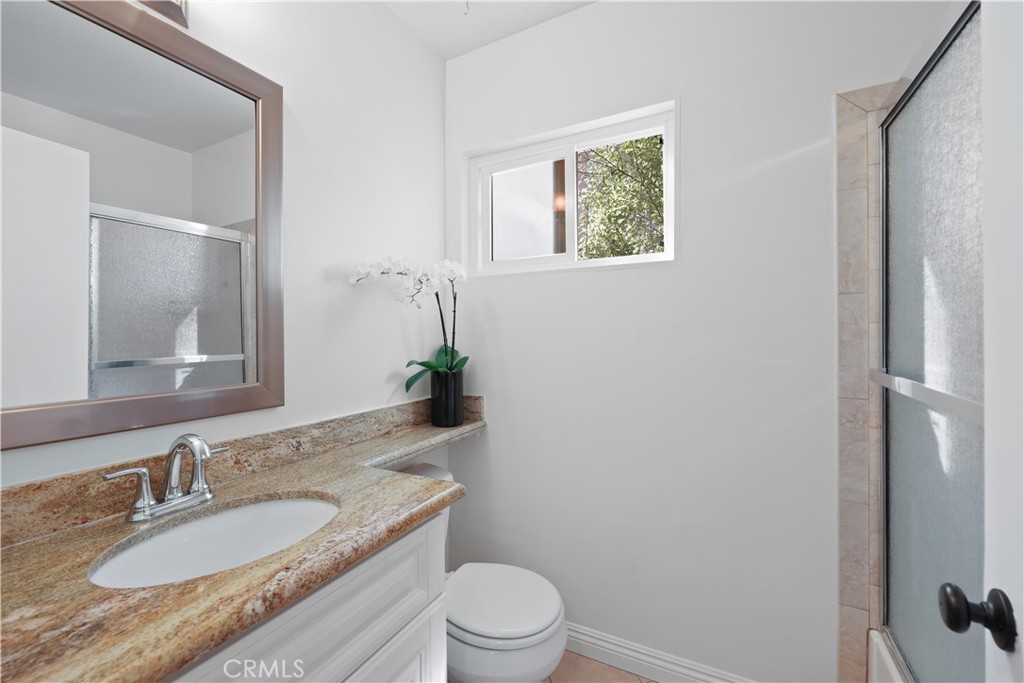 454 Seaward Road Corona del Mar, CA 92625 - Photo 16 of 33 a bathroom with a granite countertop toilet a sink and a mirror