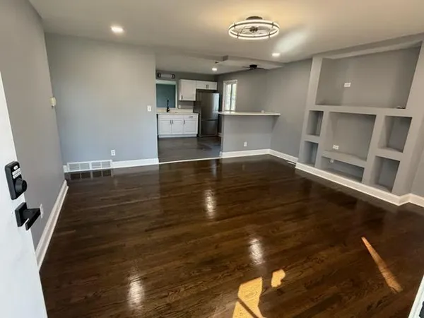 a kitchen with a refrigerator a stove top oven a sink dishwasher and white cabinets with wooden floor