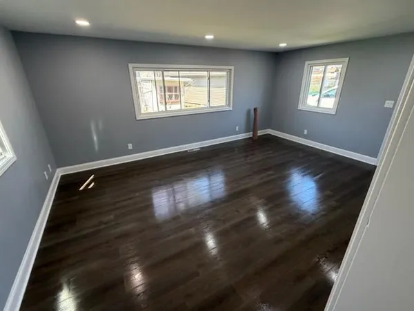 an empty room with wooden floor and windows