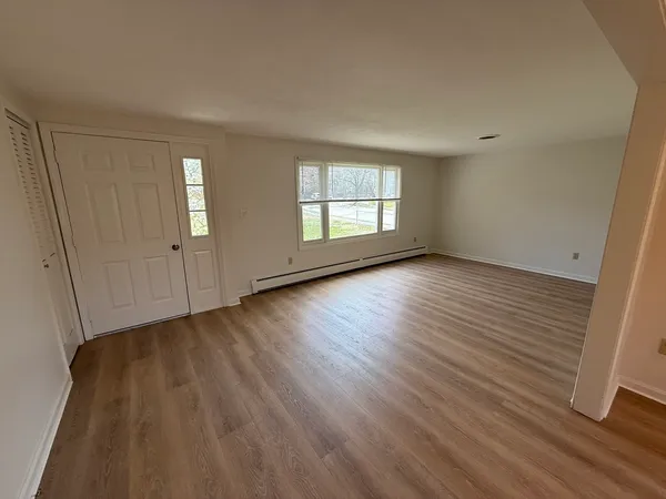 an empty room with wooden floor and windows