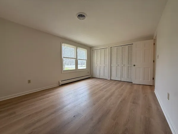 an empty room with wooden floor and windows