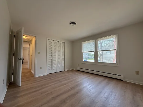 an empty room with wooden floor and windows