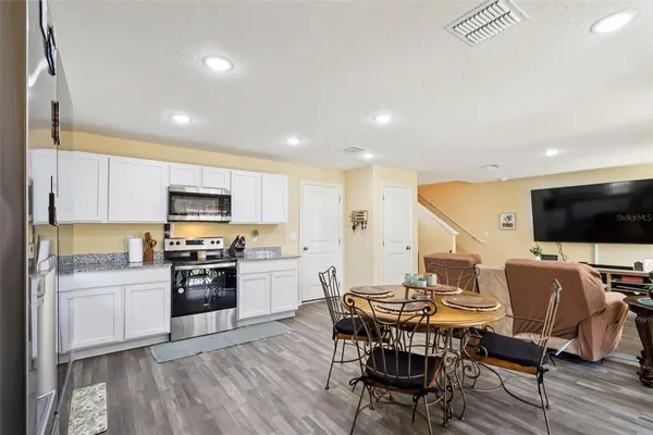 a kitchen with stainless steel appliances a dining table chairs refrigerator and microwave