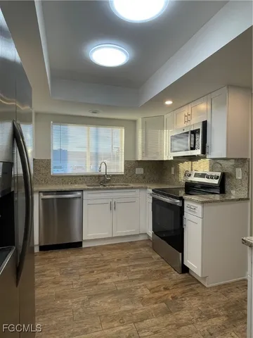 a kitchen with granite countertop a refrigerator stove top oven and sink