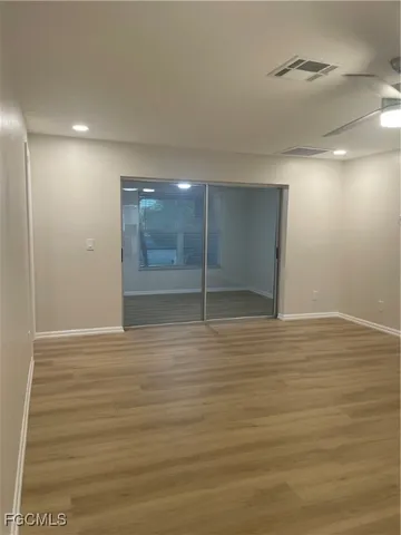 a view of an empty room with wooden floor and windows