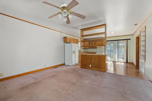 an empty room with chandelier fan and windows