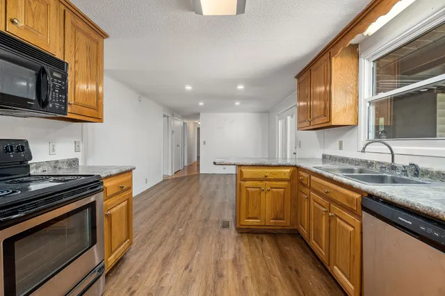 a kitchen with stainless steel appliances granite countertop wooden cabinets stove top oven and sink