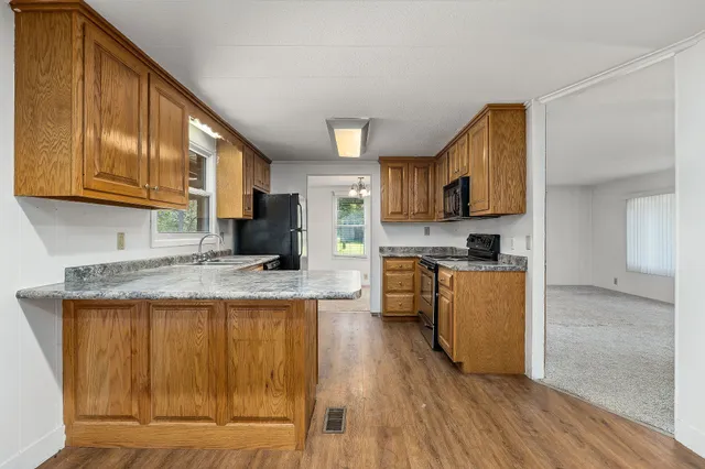 a kitchen with granite countertop wooden cabinets a stove top oven a sink and dishwasher