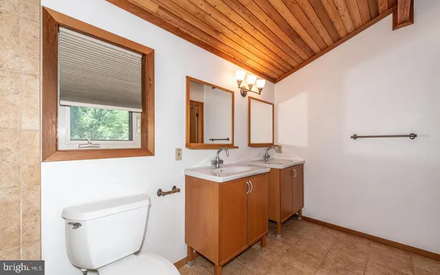a bathroom with a granite countertop sink toilet and mirror