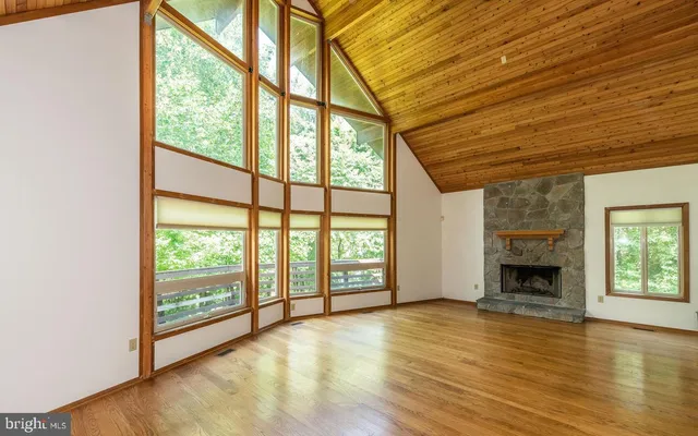 an empty room with wooden floor fireplace and windows