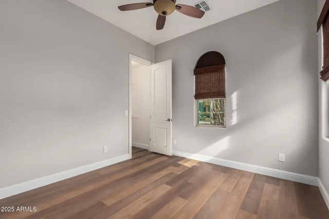 a view of an empty room with window and a ceiling fan