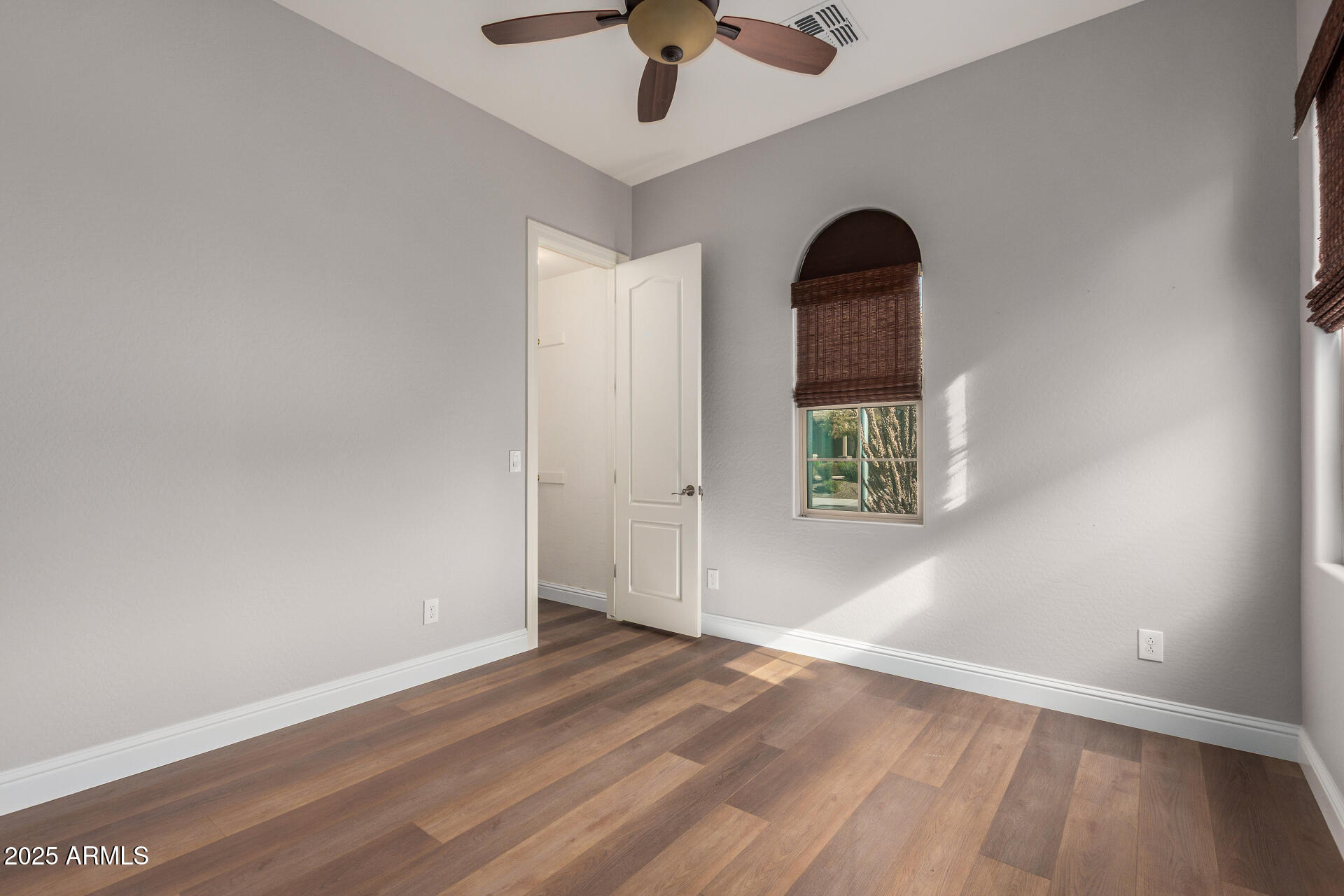 1672 South Sunset Drive Chandler, AZ 85286 - Photo 29 of 68 an empty room with wooden floor chandelier fan and windows