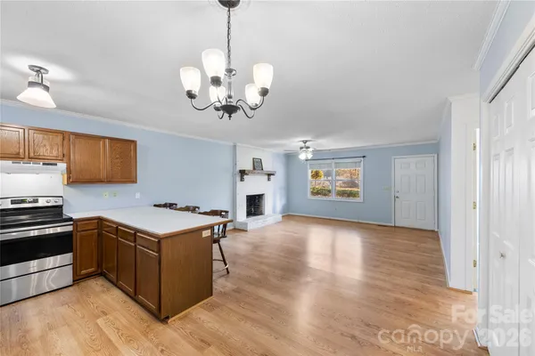 a view of a kitchen with stainless steel appliances granite countertop a stove cabinets and wooden floor