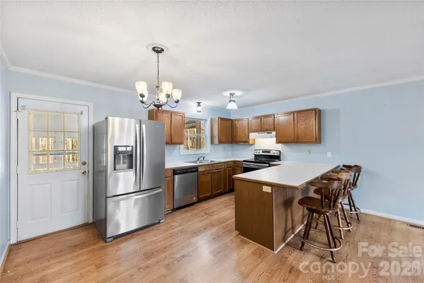 a kitchen with stainless steel appliances granite countertop a refrigerator a stove a sink dishwasher a dining table and chairs with wooden floor