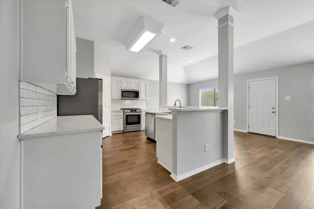 a kitchen with cabinets and wooden floor