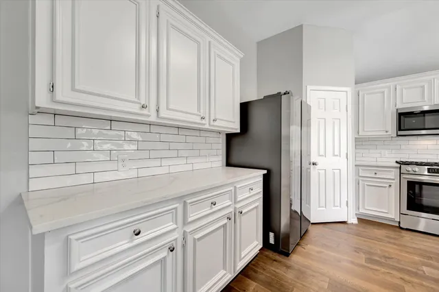 a kitchen with white cabinets and stainless steel appliances