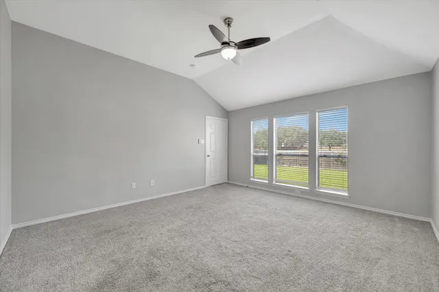 a view of an empty room with a ceiling fan and window