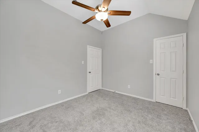 an empty room with closet and a chandelier fan