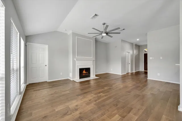 an empty room with wooden floor and ceiling fan