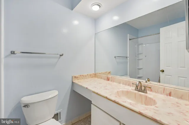 a bathroom with a granite countertop sink a toilet and a mirror
