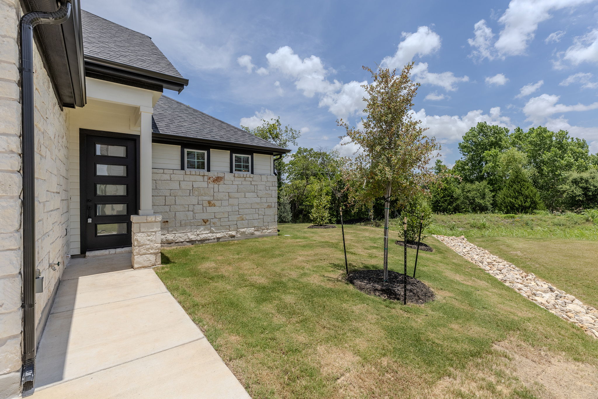 2600 Gattis School Road, Unit 1001 Round Rock, TX 78664 - Photo 34 of 40 A striking modern black entry door contrasts with a light stone and siding facade, offering a welcoming approach to this property.