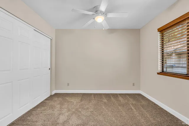 an empty room with a window and a fan