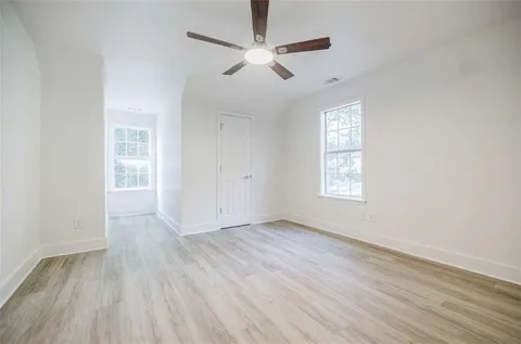 an empty room with wooden floor and ceiling fan