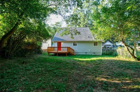 a view of a house with a yard and lawn chairs with wooden fence