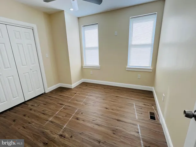 an empty room with wooden floor and closet area